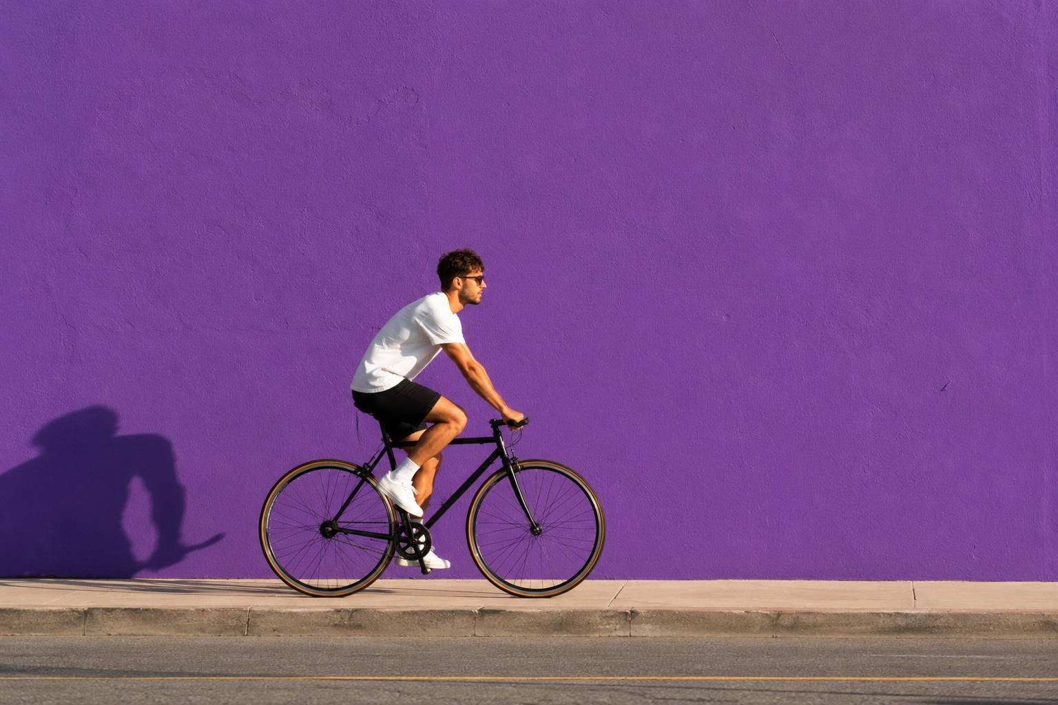 A cyclist riding past a bold purple wall